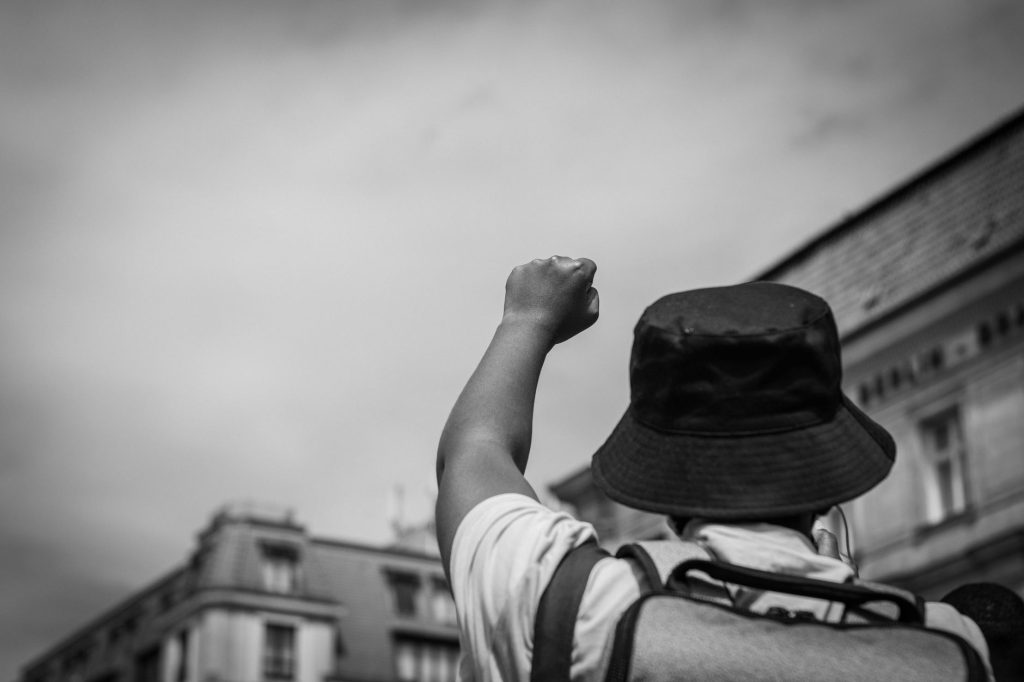 A black-and-white image of a protester raising a fist symbolizing unity and strength.